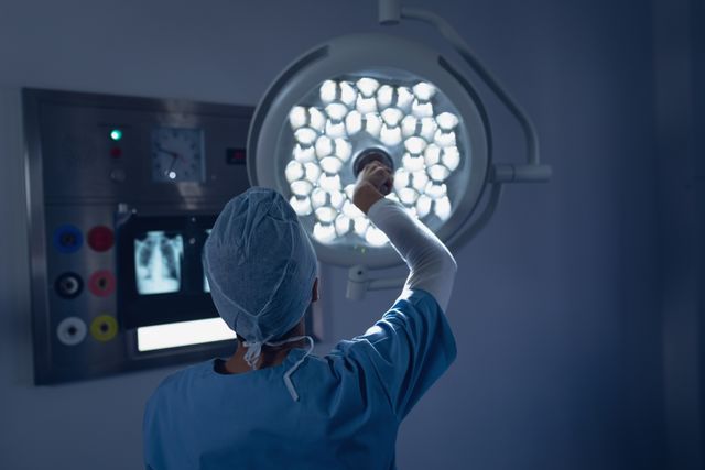Female surgeon preparing operating room by adjusting surgical light, symbolizing the meticulous nature of surgical procedures. Ideal for medical, healthcare, and hospital-related content. Can be used in articles about healthcare professionals, surgery, and medical equipment.