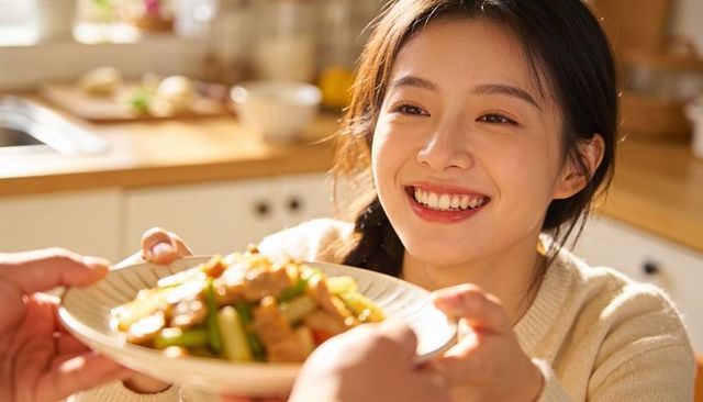 Smiling asian woman receiving stir-fry plate in cozy kitchen, sharing warm meal moment