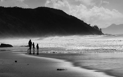 Family Strolling Silhouettes on Seashore at Dusk