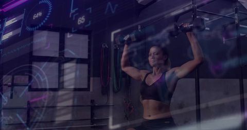 Female athlete pressing dumbbells overhead in gym with augmented reality fitness data