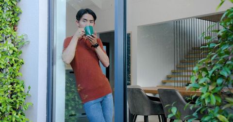 Relaxed Man Enjoying Coffee by Sliding Glass Door in Modern Home