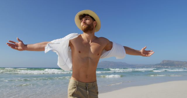 Young Man Enjoying Sunny Day at Beach with Arms Outstretched - Download Free Stock Images Pikwizard.com