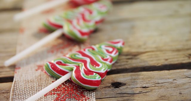 Vibrant Christmas tree shaped candies rest on wooden surface, conveying festive holiday spirit. Perfect for holiday-themed promotions, greeting cards, social media posts about festive treats or Christmas party decorations.