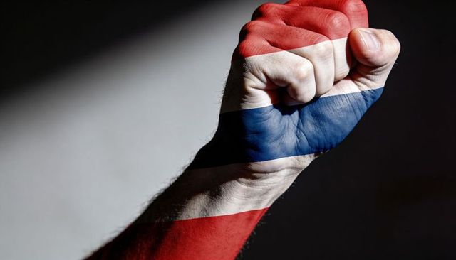 Clenching fist painted with netherlands flag stripes expressing unity, strength and patriotism