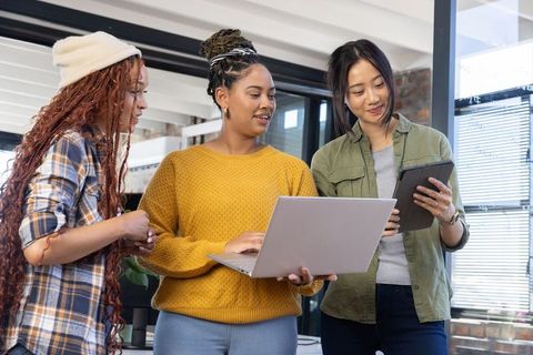 Diverse Female Colleagues Collaborating with Laptop and Tablet in Modern Office