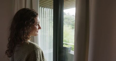 Woman gazing out sliding door in tranquil indoor-outdoor setting