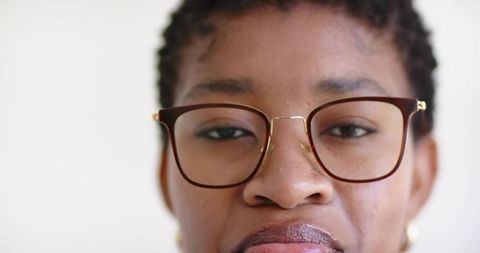 Closeup headshot of woman wearing brown eyeglasses with gold bridge, calm composed gaze