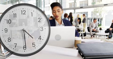 Diverse businesswoman with clock symbolizing workplace time management