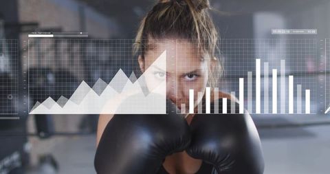 Female boxer training in industrial gym wearing black gloves displaying performance data