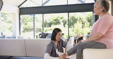 Physiotherapist Guiding Senior Woman Through Leg Exercises at Home