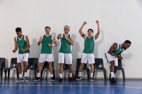 Teen basketball team celebrating on court sideline