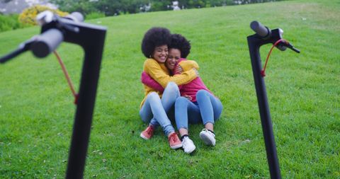 Joyful Biracial Twin Sisters Hugging with Scooters on Grass - Download Free Stock Images Pikwizard.com