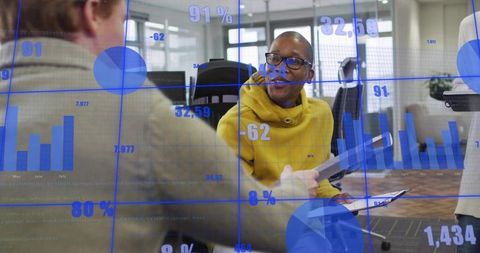 Man in Yellow Sweater Presenting Data Charts During Collaborative Team Briefing