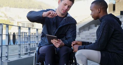 Educator in Wheelchair Engaging Teen with Interactive Tablet Outdoors