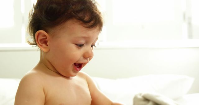 Joyful Toddler with Curly Hair Playing on Bed in Sunlit Bedroom - Download Free Stock Images Pikwizard.com