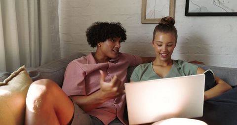 Diverse Couple Relaxing on Sofa with Laptop at Home