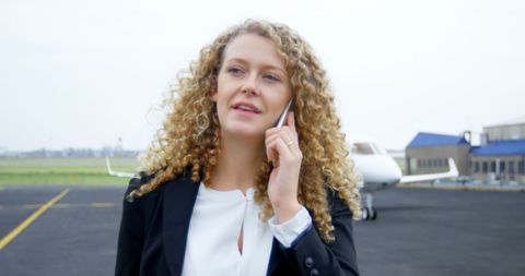 Confident Businesswoman Engaged in Call at Airport Tarmac