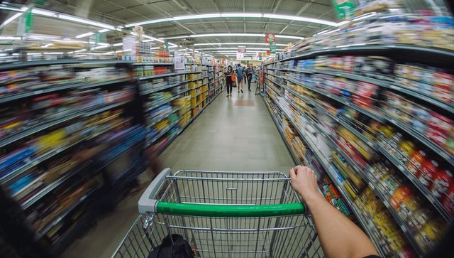 Pov pushing shopping cart down supermarket aisle with green handle and motion blur