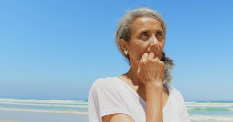 Thoughtful senior woman pondering at sunny beach
