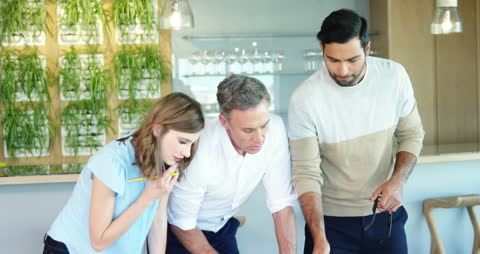 Diverse Team Collaborating on Project Blueprint in Modern Office