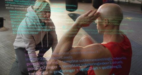 Trainer guiding man performing crunches on gym mat with medicine ball and code overlay