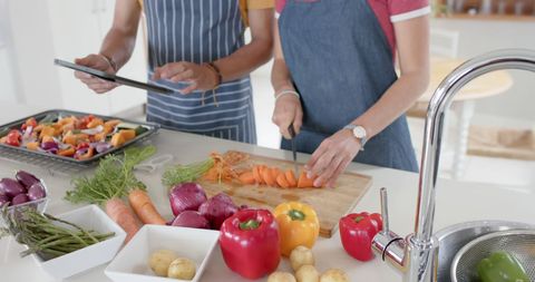 Couple Using Tablet While Preparing Healthy Meal at Home