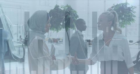 Businesswomen Shaking Hands with Digital Financial Charts Overlay