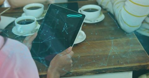 Chinese woman holding tablet and viewing augmented digital network overlay in cozy cafe