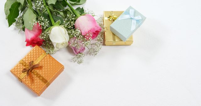 Colorful roses placed near elegant gift boxes on white background. Can be used for advertisements related to celebrations, romantic events, birthdays, anniversaries, and elegant occasions. Ideal for use in greeting cards, invitations, and promotional materials.