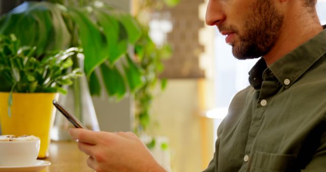 Man Using Smartphone in Cafe Setting, Focused on Screen - Download Free Stock Images Pikwizard.com