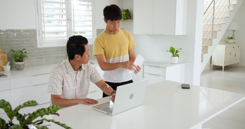 Father and Son Discussing Bills in Bright Kitchen