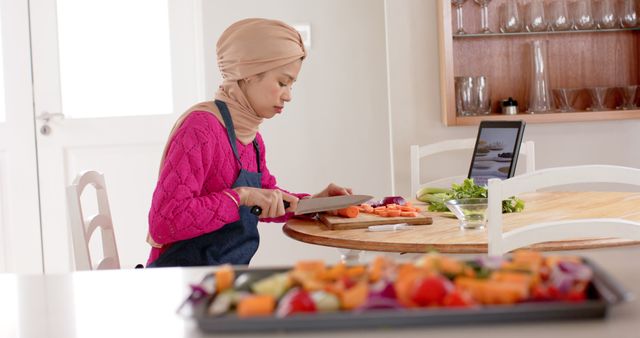 Woman in Hijab Following Recipe on Tablet, Cutting Vegetables - Download Free Stock Images Pikwizard.com