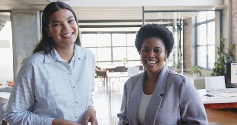 Two Female Colleagues Smiling in Modern Open Office