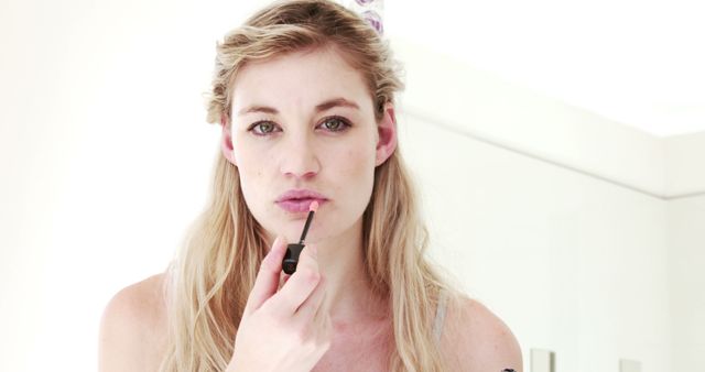 Blonde Woman Applying Lip Gloss in Minimalistic Setting - Download Free Stock Photos Pikwizard.com
