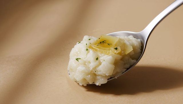 Creamy Arborio Risotto Spoonful with Melting Butter and Parsley on Warm Beige Surface