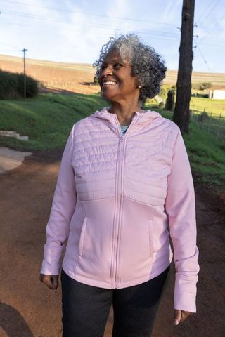 Senior African American Woman Enjoying Peaceful Country Walk in Pink Jacket