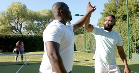 Friends Celebrating Victory with High-Five on Tennis Court