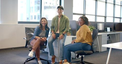 Smiling diverse team collaborating in modern bright office with casual seating