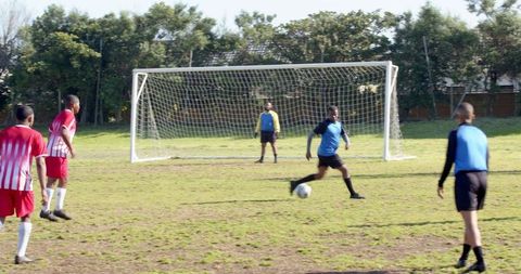 African American Men Playing Soccer on Grass Field by Goal