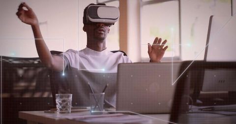 Tech professional navigating virtual workspace using VR headset at office desk with laptop