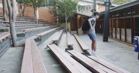 Energetic boy jumping over benches in school courtyard