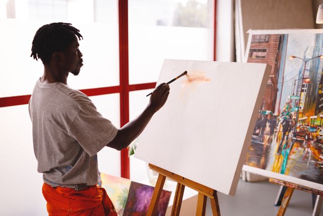 African american male painter at work painting on canvas in art studio. creation and inspiration at an artist painting studio.