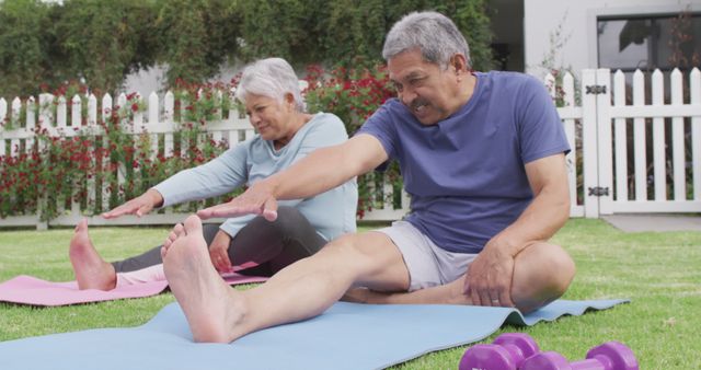 Happy senior diverse couple practicing yoga in garden. Spending quality time at home, retirement and lifestyle concept.