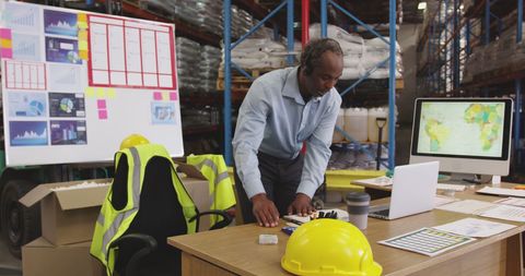 African American Warehouse Manager Using Laptop for Inventory Check