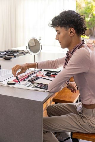 Man Applying Eyeshadow at Modern Kitchen Island with Laptop