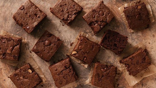 Rustic chocolate chip brownies cut into squares on parchment and wooden board