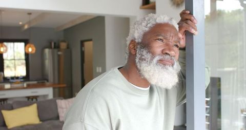 Reflective Mature Man Gazing Out Window in Stylish Home Interior
