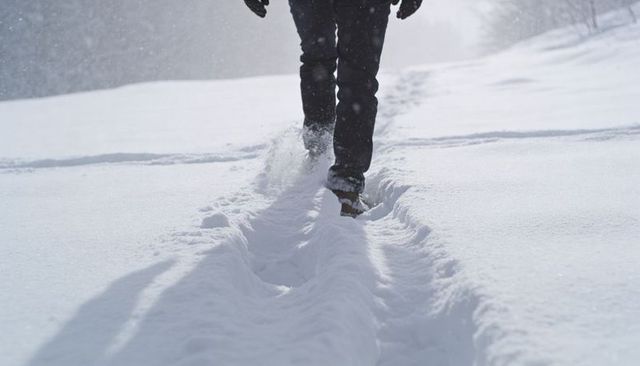 Walking through deep snow leaving parallel tracks in winter field
