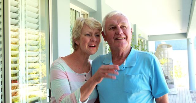Senior couple pointing away at home