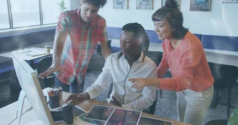 Creative team collaborating at computer reviewing printed proofs through dotted glass